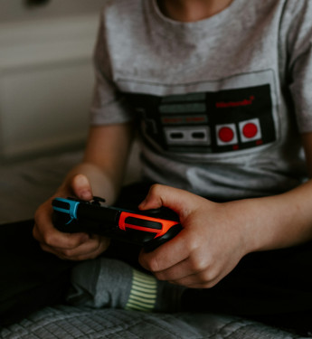 Ein Kind, dass einen Controller in der Hand hält und Videospiele spielt