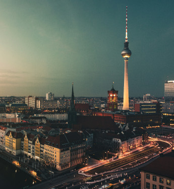 Panoramaansicht von Berlin bei Dämmerung mit Fluss, Berliner Dom, Fernsehturm und beleuchteten Gebäuden.