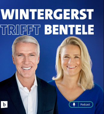 Zwei Personen vor blauem Hintergrund: links mit grauen Haaren im dunklen Anzug, rechts mit blonden Haaren im blauen Oberteil.