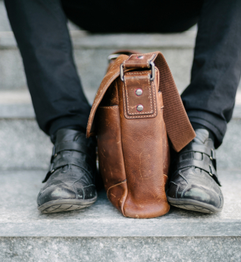 Person auf Treppe mit Ledertasche 