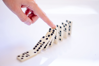 Kippende Dominosteine werden durch einen Finger gestoppt