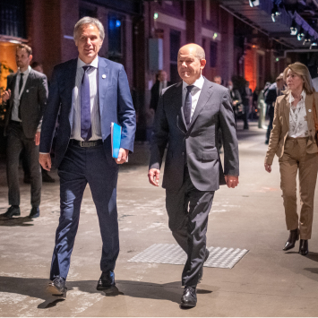 Achim Berg und Olaf Scholz auf dem Digital-Gipfel 2022 nebeneinander laufend und in einer Unterhaltung.