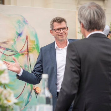 Thorsten Dirks und Achim Berg stehen gemeinsam auf der Bühne und geben sich einen Handschlag.