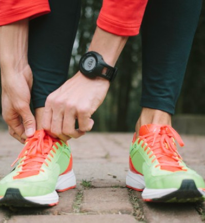 Person mit Laufschuhen und Tracking/Fitness-Armband