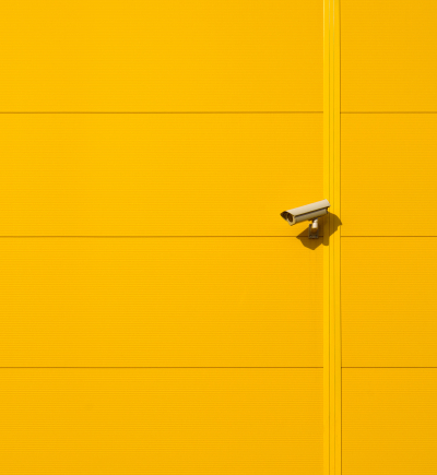 Überwachungskamera an gelber Wand