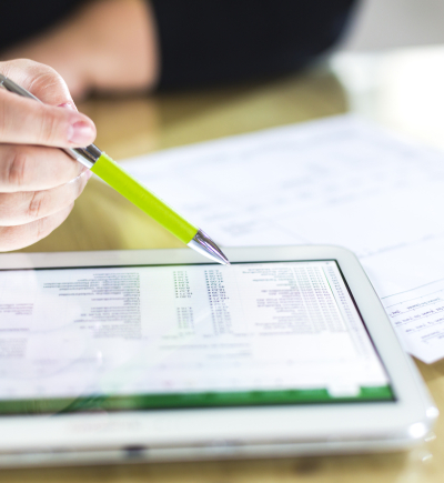 Person sitzt vor einer Rechnung vor Papier und einem Tablet