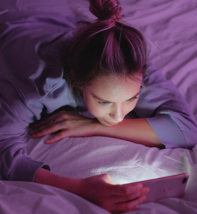 junge Frau mit Smartphone im Bett