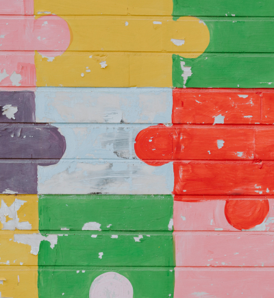 Bunte Puzzleteile auf eine Backsteinmauer gemalt