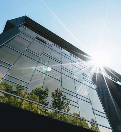 Modernes verglastes Haus in der Sonne mit Baumspiegelung