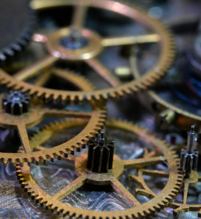 Mehrere ineinandergreifende Zahnräder eines mechanischen Uhrwerks in Nahaufnahme.