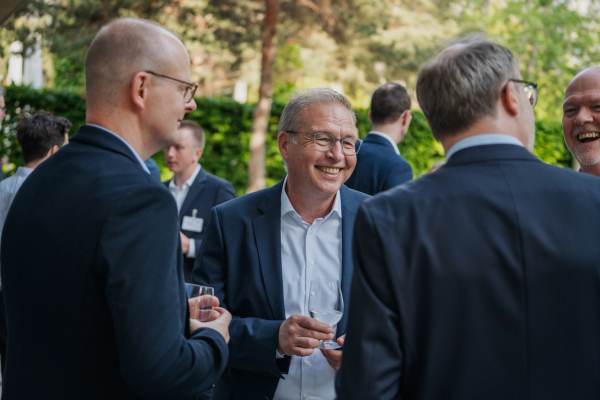 Eine Gruppe von Bitkom Forum Recht-Teilnehmern steht draußen und unterhält sich. Bäume im Hintergrund.
