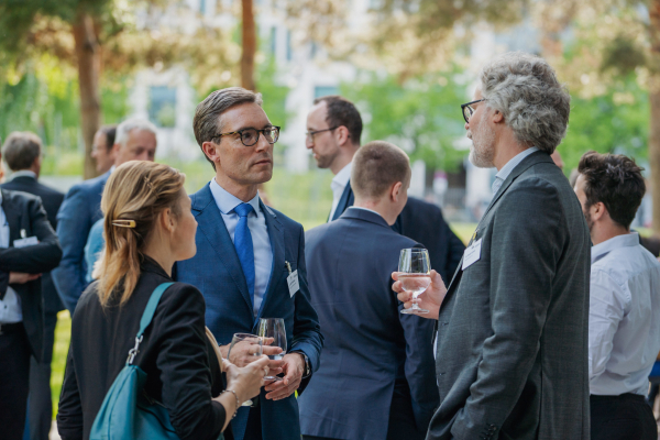 Eine Gruppe von Bitkom Forum Recht-Teilnehmern steht draußen und unterhält sich. Bäume im Hintergrund.