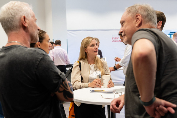 Impression vom Networking beim BFOSS25, mehrere Personen unterhalten sich angeregt an einem Stehtisch