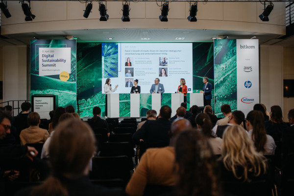 Panel discussion at Digital Sustainability Summit 2026 with four speakers at white podiums and an audience in the background.