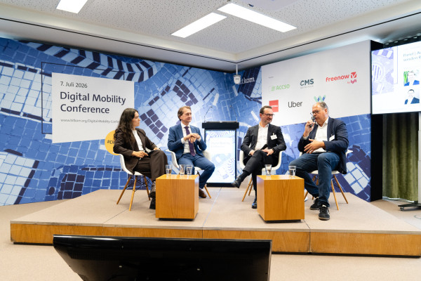 Vier Personen auf einer Bühne bei der Digital Mobility Conference am 7. Juli 2026, eine spricht ins Mikrofon.